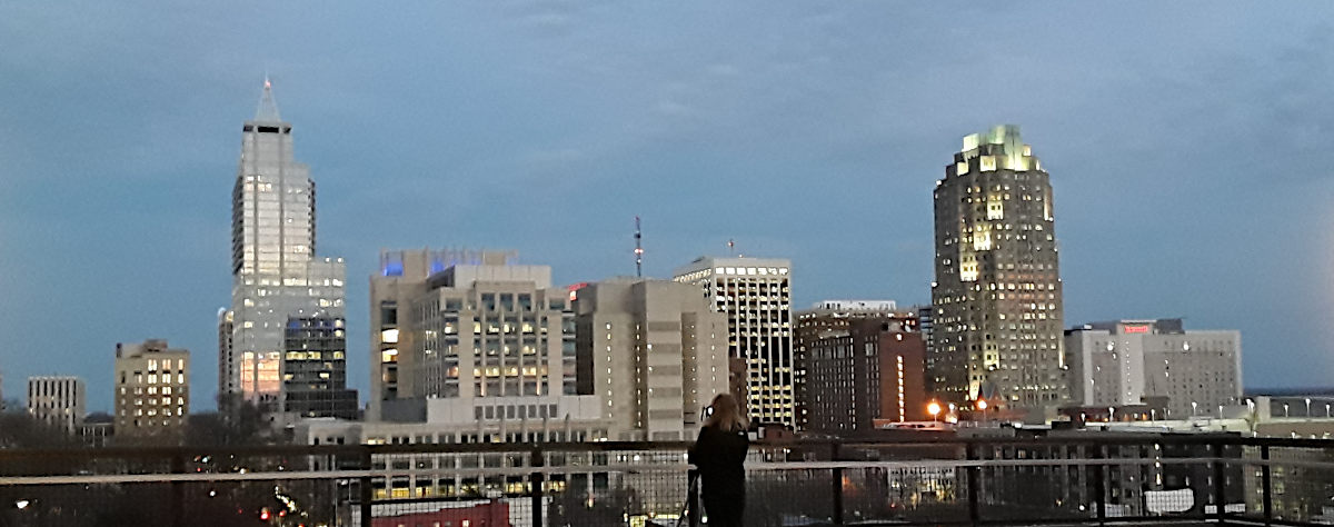 Downtown Raleigh skyline at dusk, with a photographer in the foreground